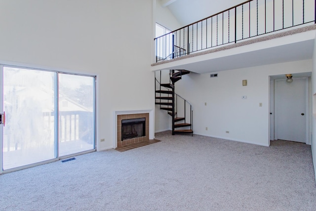 unfurnished living room featuring a high ceiling, a tile fireplace, and carpet floors