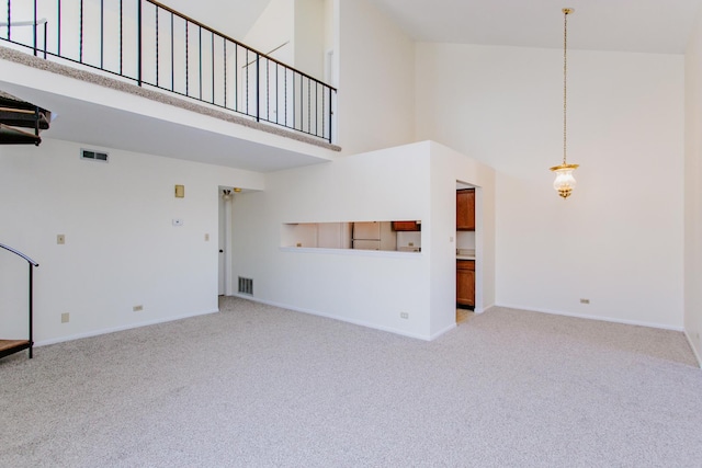 unfurnished living room featuring a towering ceiling and light colored carpet