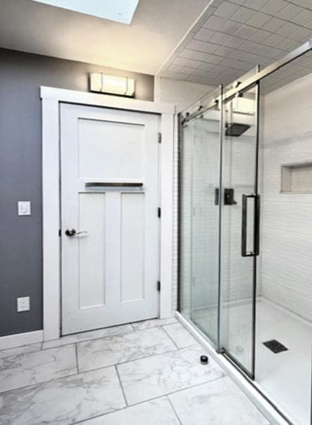 full bathroom featuring marble finish floor, a stall shower, and baseboards