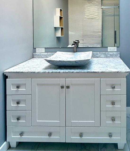 bathroom featuring baseboards, a stall shower, and vanity