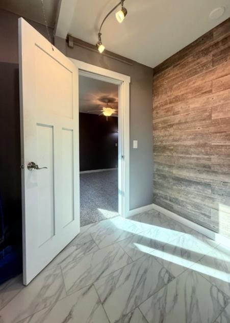 interior space featuring wooden walls, marble finish floor, and ceiling fan