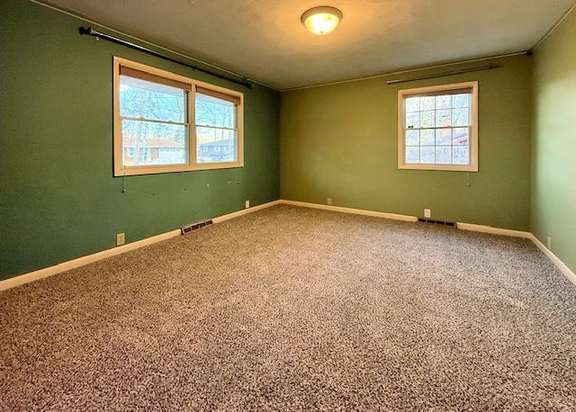 empty room featuring visible vents, baseboards, and carpet