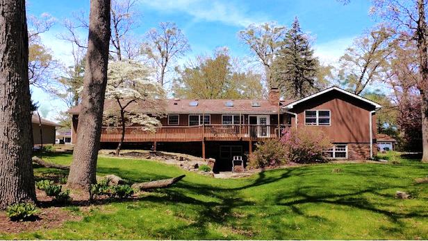 back of house with a wooden deck, a lawn, and a chimney