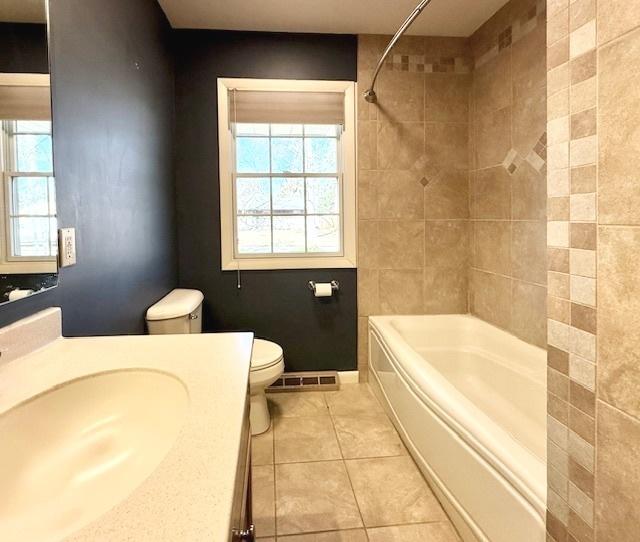 full bathroom with vanity, washtub / shower combination, visible vents, tile patterned floors, and toilet