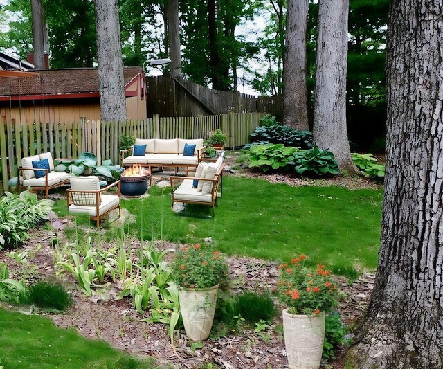 view of yard with an outdoor living space with a fire pit and fence