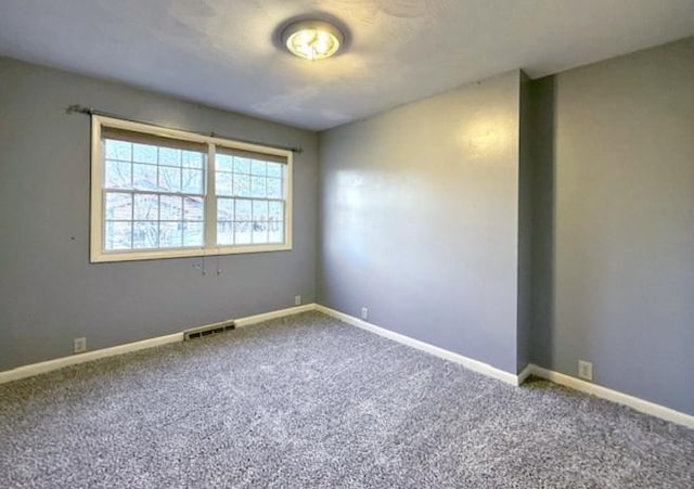 empty room featuring visible vents, baseboards, and carpet