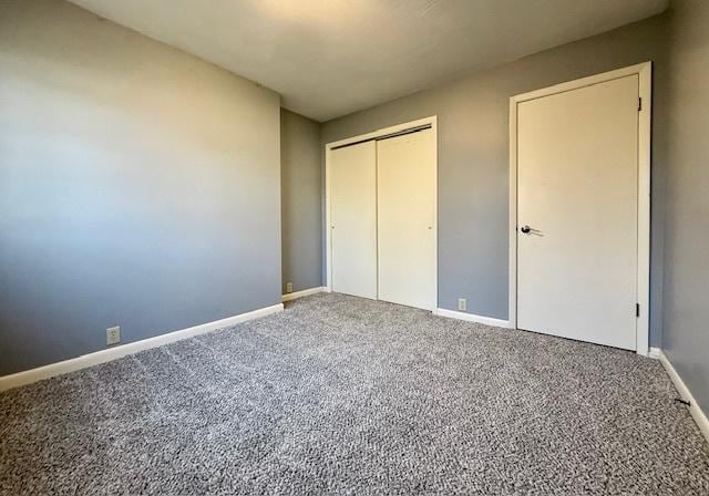 unfurnished bedroom with a closet, baseboards, and carpet flooring