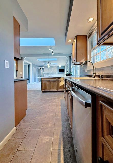 kitchen featuring a sink, backsplash, dishwasher, and a ceiling fan