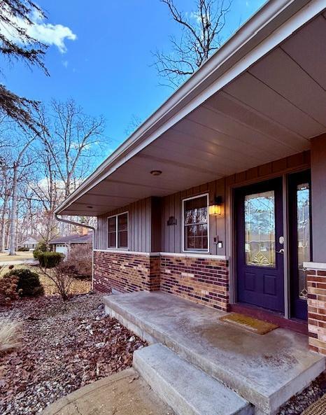 view of exterior entry with a porch and brick siding