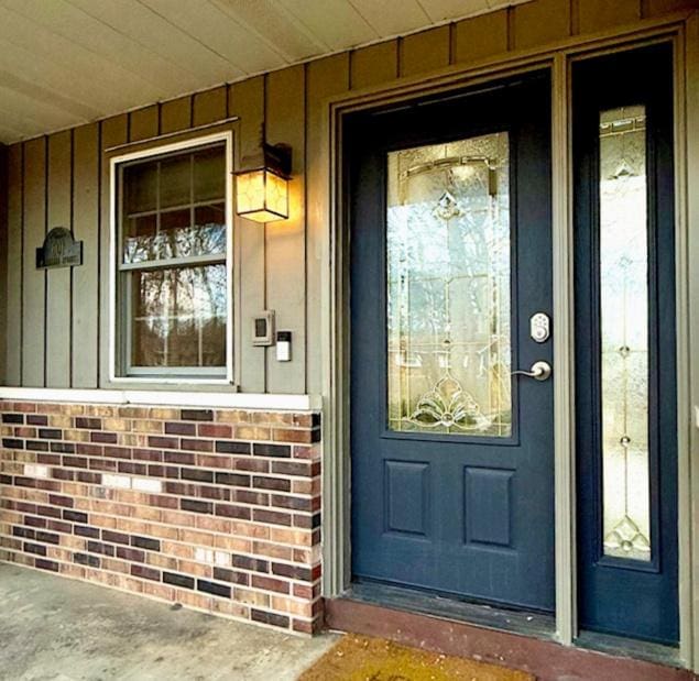 doorway to property with board and batten siding and a porch