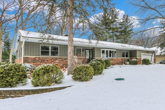 ranch-style home featuring brick siding, an attached garage, and board and batten siding