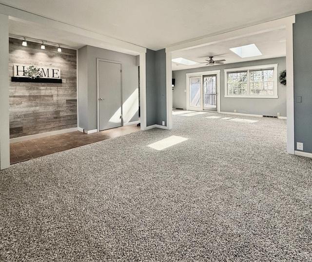 interior space featuring carpet flooring, baseboards, ceiling fan, and track lighting