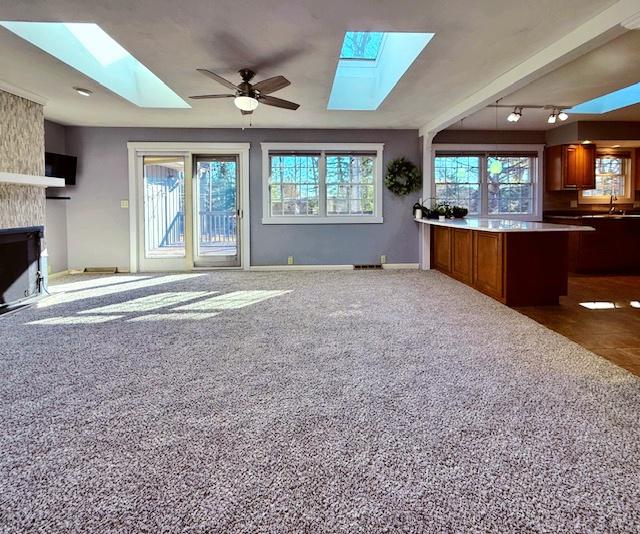 unfurnished living room featuring a healthy amount of sunlight, a skylight, and a large fireplace