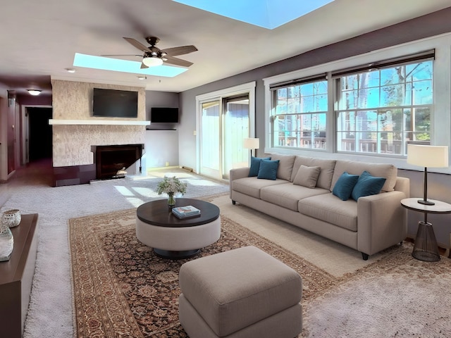 living area with ceiling fan, a wealth of natural light, and a skylight