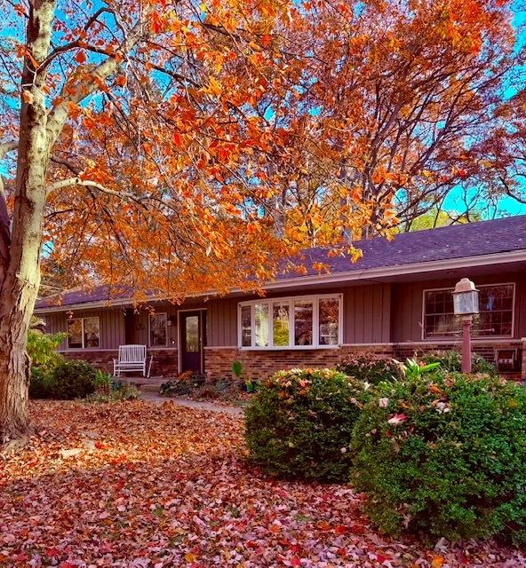 ranch-style house featuring brick siding, a porch, and board and batten siding