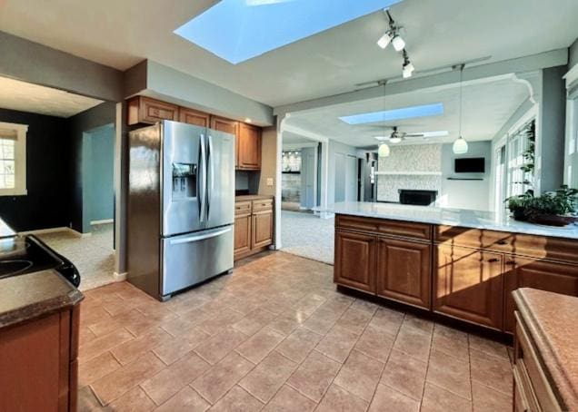 kitchen with stainless steel fridge with ice dispenser, decorative light fixtures, open floor plan, a skylight, and a ceiling fan