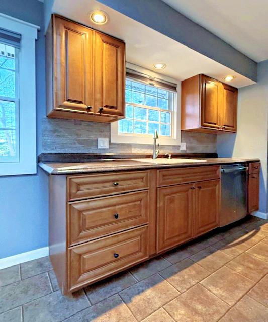 kitchen featuring dishwasher, baseboards, tasteful backsplash, and a sink