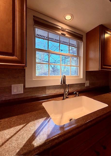 room details with a sink, tasteful backsplash, and dark countertops