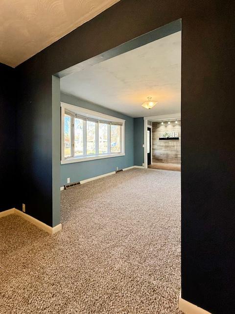 spare room featuring visible vents, baseboards, and carpet