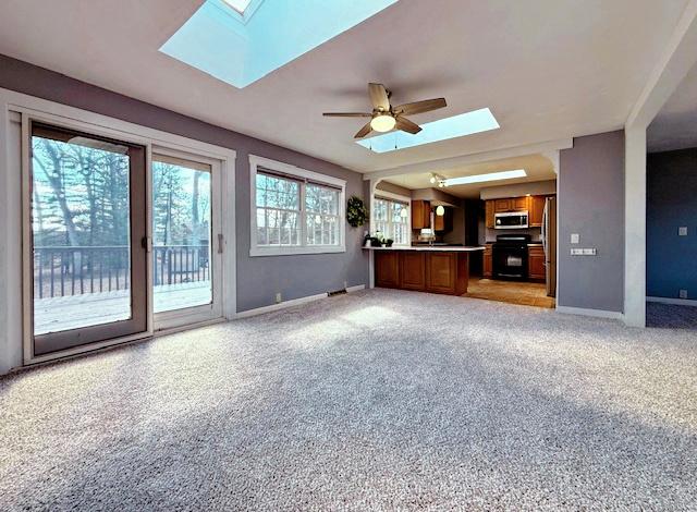 unfurnished living room with baseboards, a skylight, and a ceiling fan