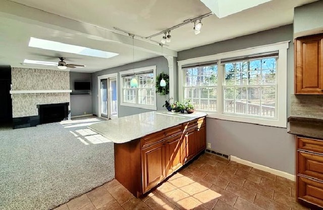 kitchen with a peninsula, a skylight, a fireplace, and a healthy amount of sunlight