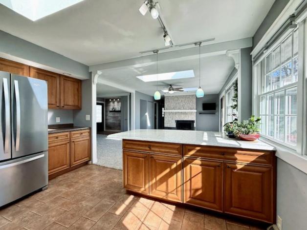 kitchen with a skylight, a fireplace, brown cabinets, and freestanding refrigerator