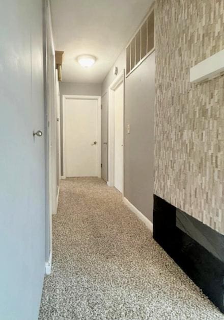 hallway with visible vents, baseboards, and carpet flooring