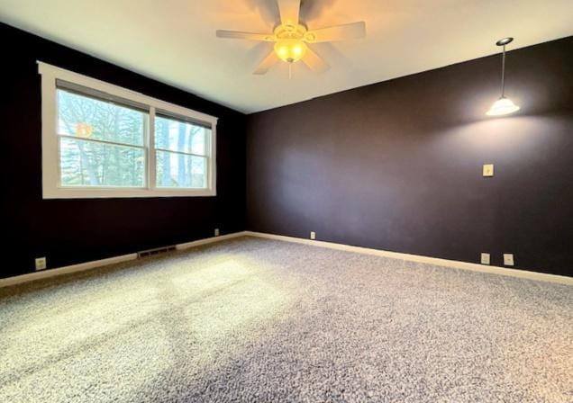 carpeted spare room featuring visible vents, baseboards, and a ceiling fan