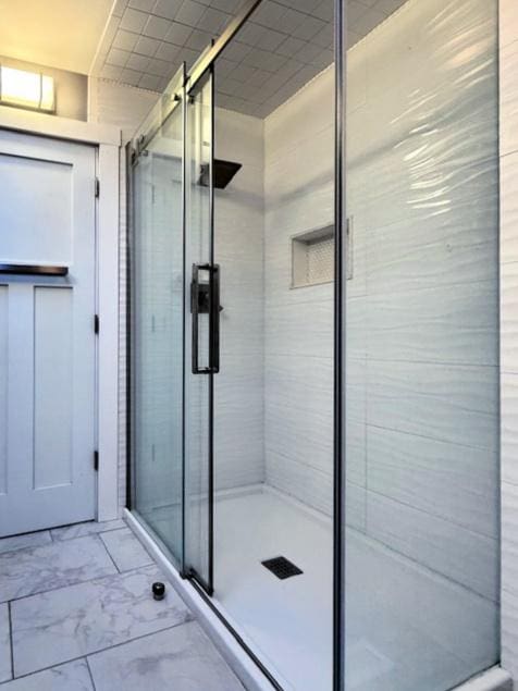 full bath with marble finish floor and a shower stall