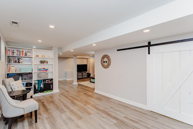 sitting room with a barn door and light wood-type flooring