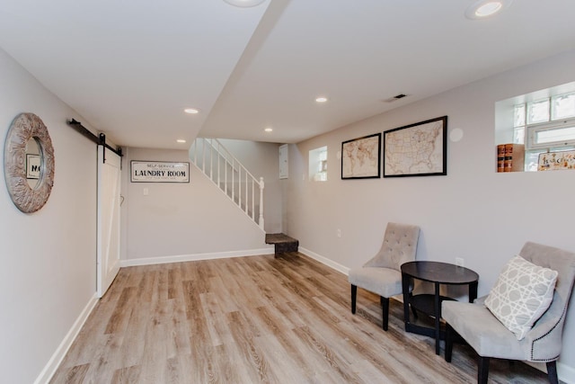 living area with light hardwood / wood-style flooring and a barn door