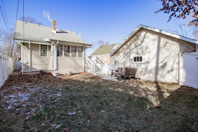 rear view of property with central AC unit and a lawn