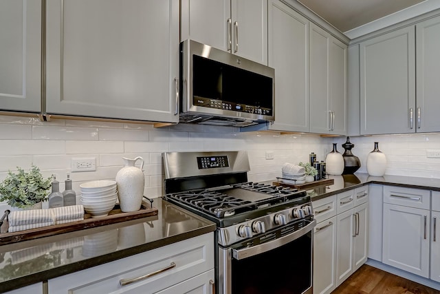 kitchen featuring tasteful backsplash, appliances with stainless steel finishes, dark wood-type flooring, and dark stone counters