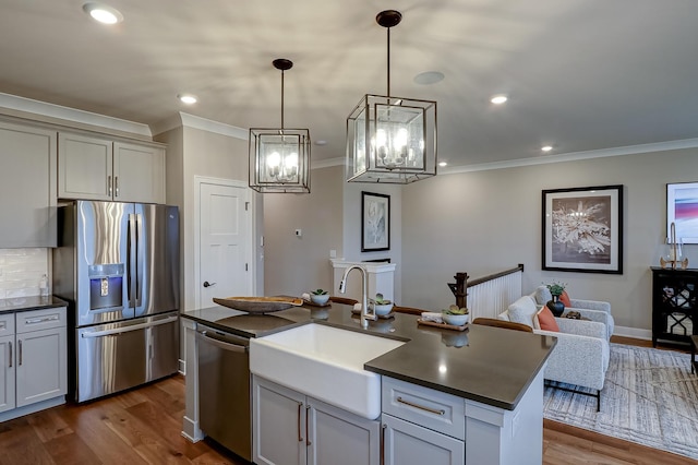 kitchen with a kitchen island with sink, hanging light fixtures, backsplash, stainless steel appliances, and dark hardwood / wood-style floors