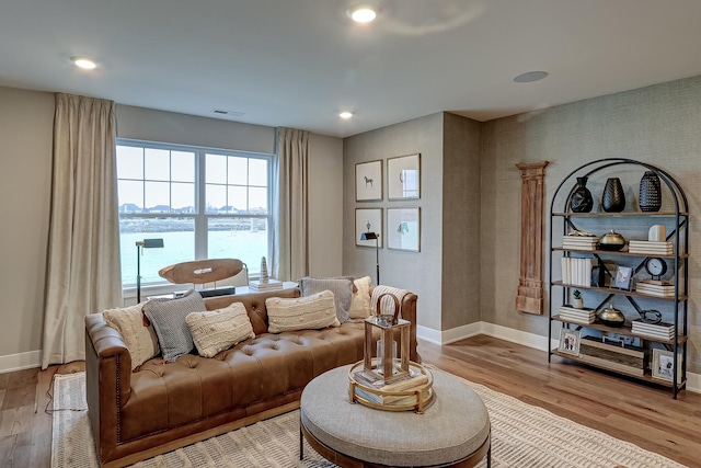 living room with a water view and light hardwood / wood-style flooring