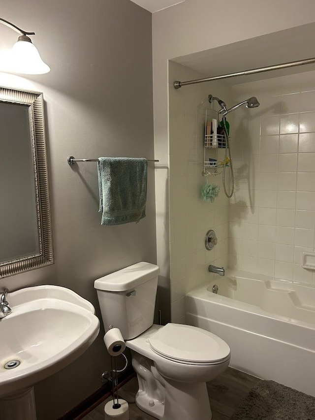 full bathroom with tiled shower / bath combo, wood-type flooring, sink, and toilet