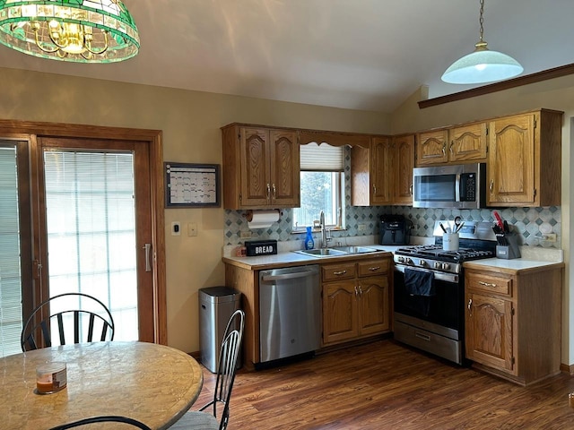 kitchen featuring lofted ceiling, sink, hanging light fixtures, appliances with stainless steel finishes, and dark hardwood / wood-style floors