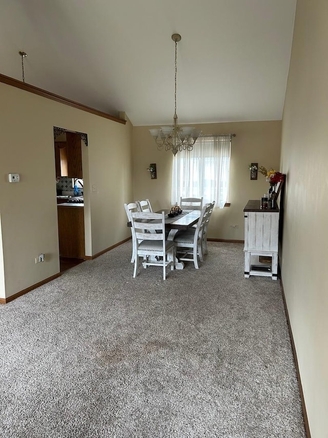 dining area with crown molding, carpet flooring, and a chandelier