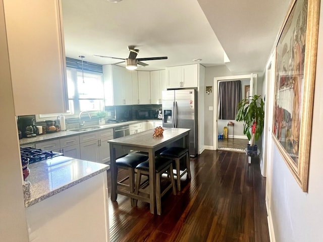 kitchen with backsplash, stainless steel appliances, light stone countertops, white cabinets, and decorative light fixtures