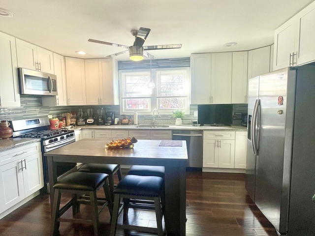 kitchen with tasteful backsplash, sink, white cabinets, and appliances with stainless steel finishes