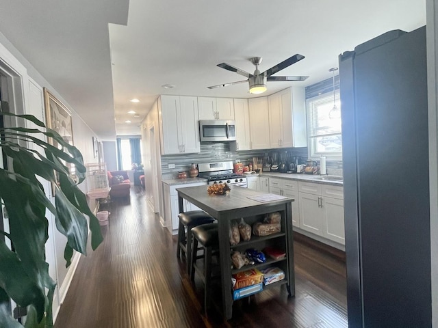 kitchen with stainless steel appliances, white cabinetry, dark wood-type flooring, and backsplash