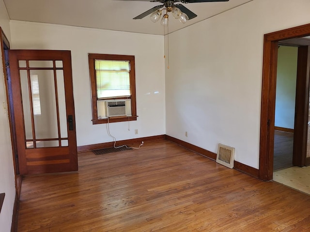 empty room featuring cooling unit, wood-type flooring, and ceiling fan