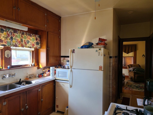 kitchen featuring sink, backsplash, and white appliances