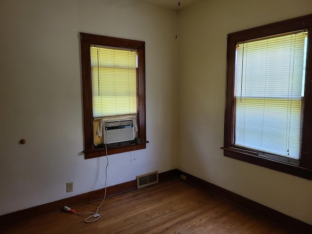 spare room with hardwood / wood-style floors, a wealth of natural light, and cooling unit