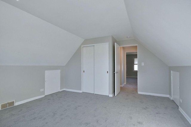 bonus room with vaulted ceiling and light carpet