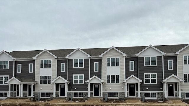 view of front of house featuring stone siding and a shingled roof