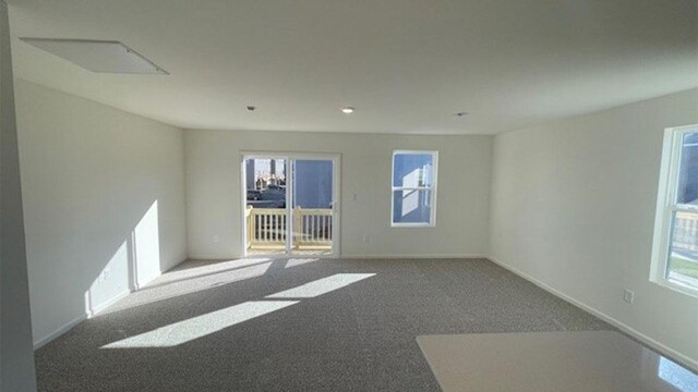 carpeted spare room with plenty of natural light and baseboards