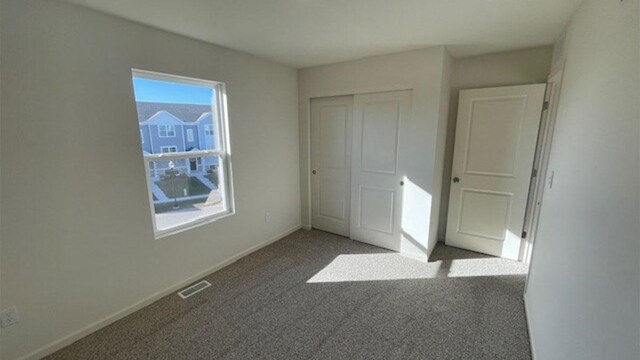 unfurnished bedroom with a closet, visible vents, baseboards, and carpet floors