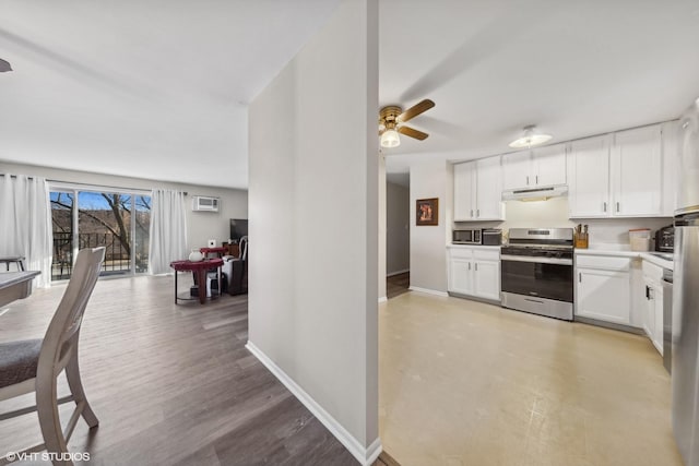 kitchen with ceiling fan, appliances with stainless steel finishes, white cabinetry, a wall unit AC, and light hardwood / wood-style floors