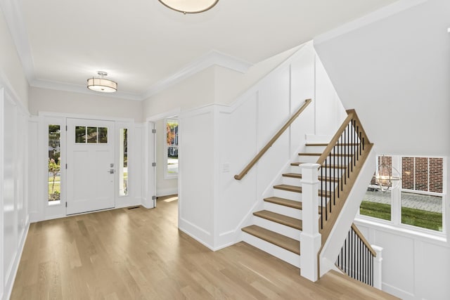 foyer entrance with crown molding and light wood-type flooring